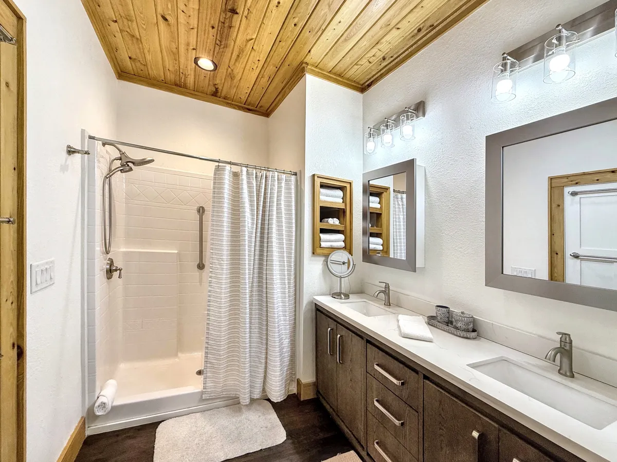 A spa-inspired bathroom with a spacious shower area, double sink vanity, large mirrors, and a wooden ceiling. The space feels calm and refreshing, perfect for unwinding after a day of adventure.