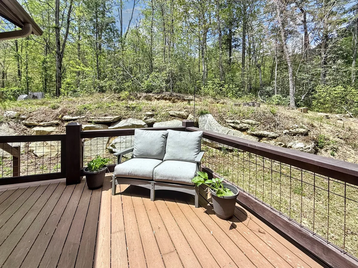 A comfortable seating area is arranged on a wooden deck, with soft cushions and greenery forming a peaceful backdrop. The inviting chairs provide a perfect spot for reading, sipping wine, or simply soaking in the tranquility of the outdoors.